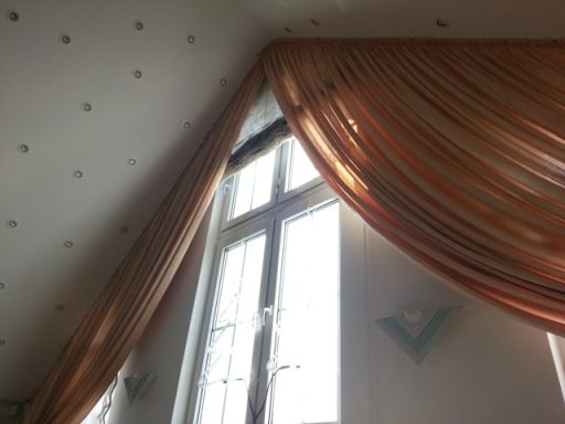 Helle Fenster mit eleganten, goldenfarbigen Vorhängen in einem Raum.